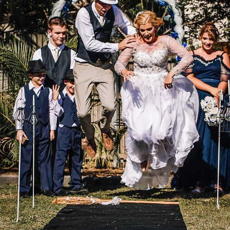 A couple jump a broomstick at a wedding ceremony performed by Jenny Stevens in Townsville
